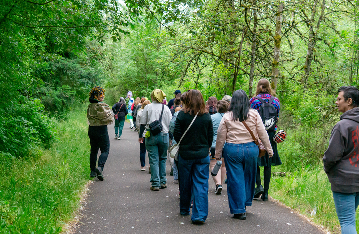 a group of people walk along a lush, paved path in portland oregon